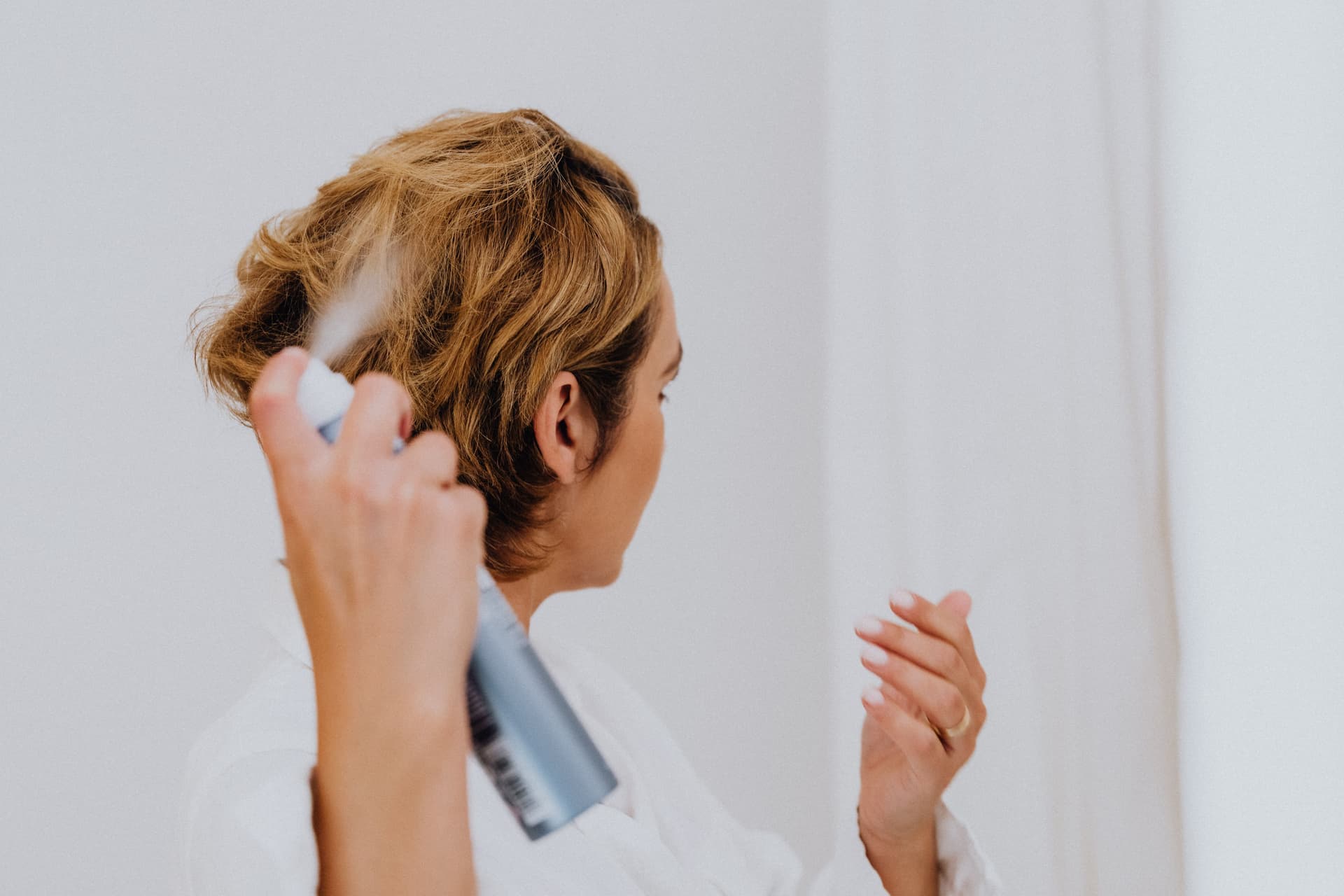A styling spray bottle beside hair tools on a light surface