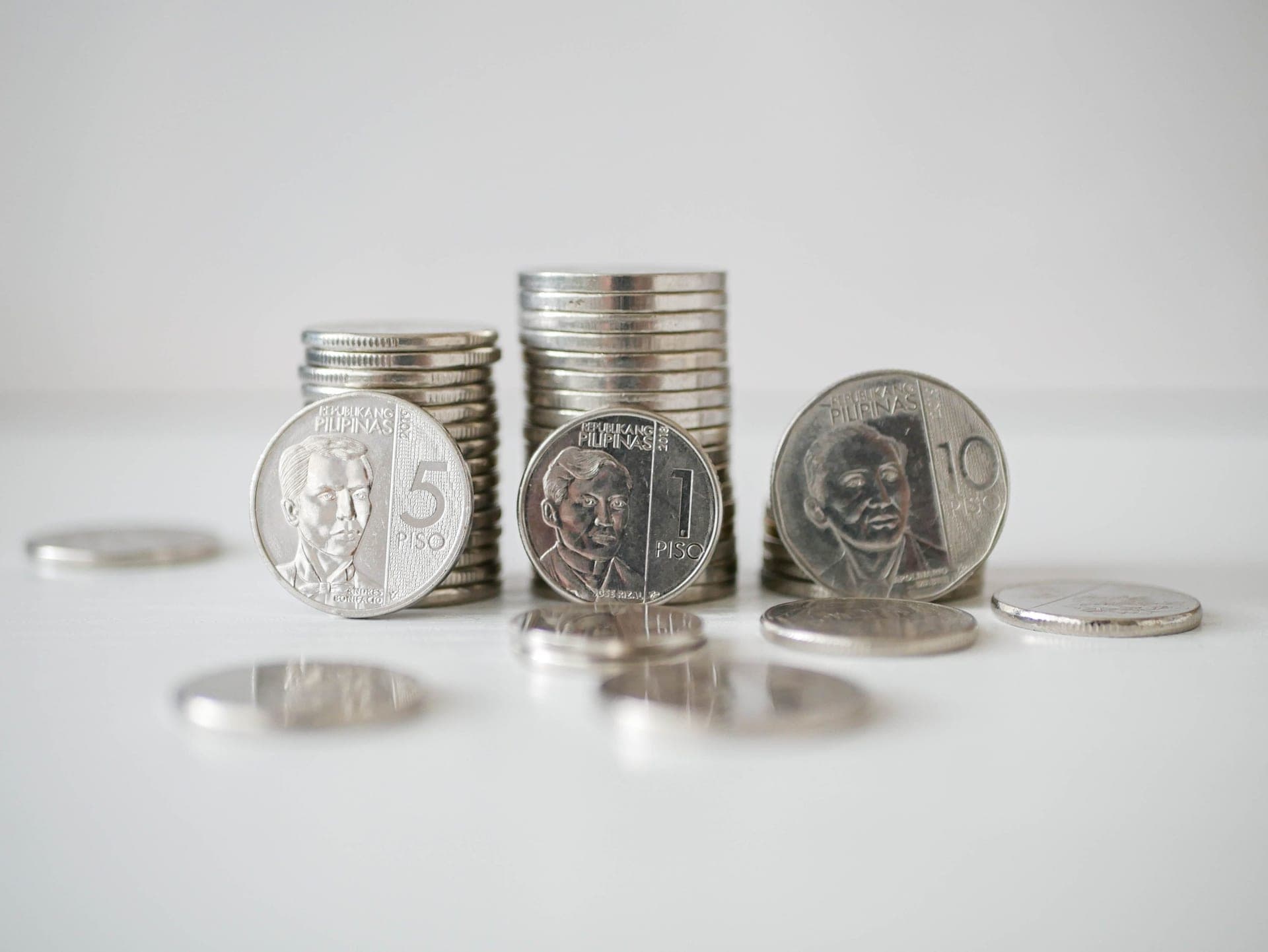 Stacked coins beside a notebook on a desk